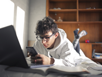 Young person on phone and laptop